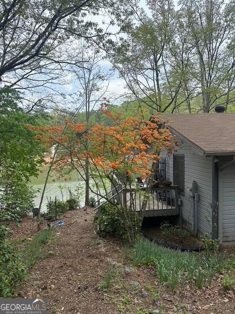 view of side of property with a deck and roof with shingles