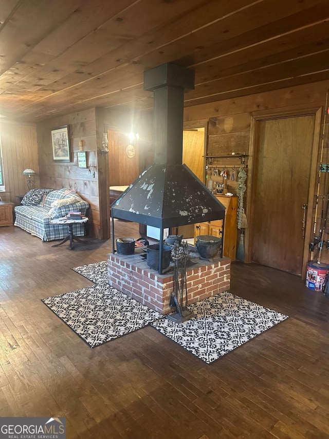 sitting room featuring a wood stove, hardwood / wood-style flooring, and wooden walls