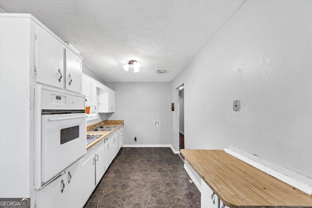 844 Oak St NW, Atlanta, GA 30318 - kitchen featuring a sink, oven, a textured ceiling, stone finish flooring, and white cabinets