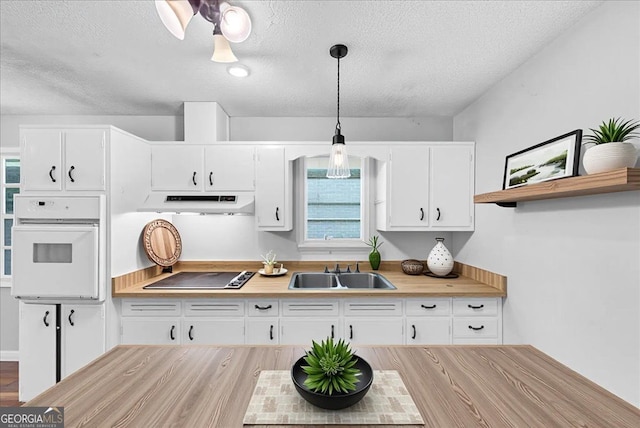 844 Oak St NW, Atlanta, GA 30318 - kitchen featuring a textured ceiling, under cabinet range hood, a sink, black electric cooktop, and oven