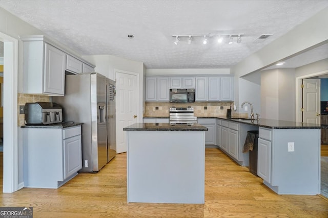 1314 Durham Ter, Mcdonough, GA 30252 - kitchen with stainless steel appliances, a peninsula, gray cabinetry, a center island, and backsplash