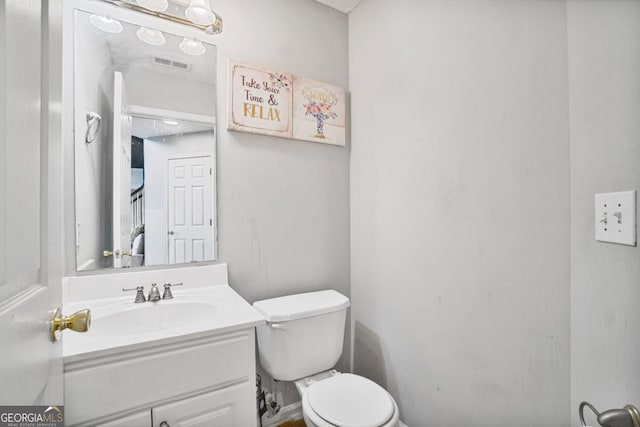 bathroom featuring toilet, vanity, and visible vents