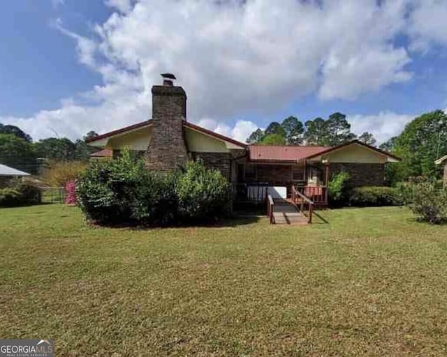 back of house with a yard and a chimney