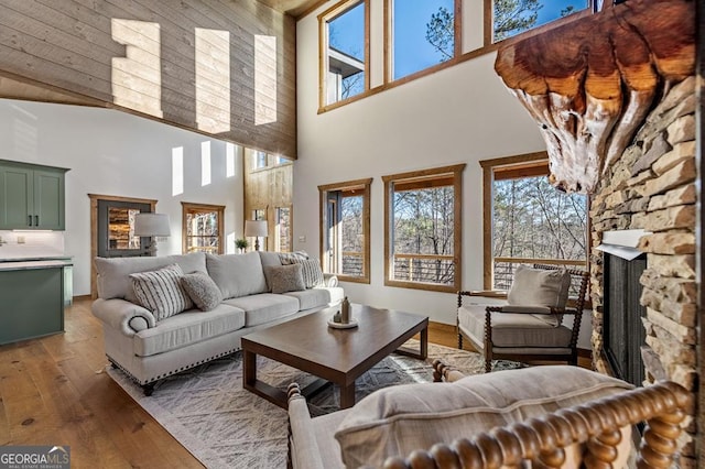 living room with baseboards, hardwood / wood-style floors, a fireplace, and a towering ceiling