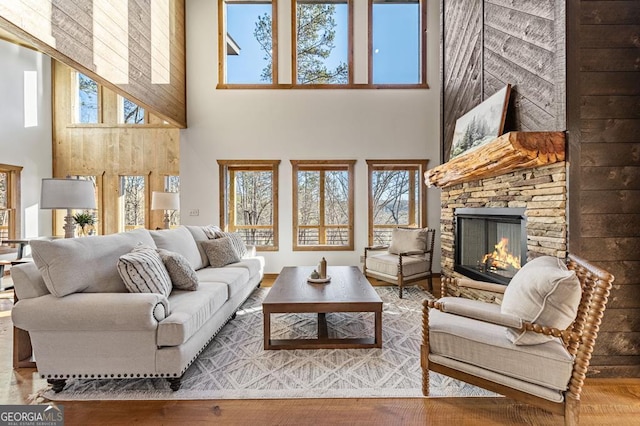 living area with a fireplace, a high ceiling, plenty of natural light, and wood finished floors