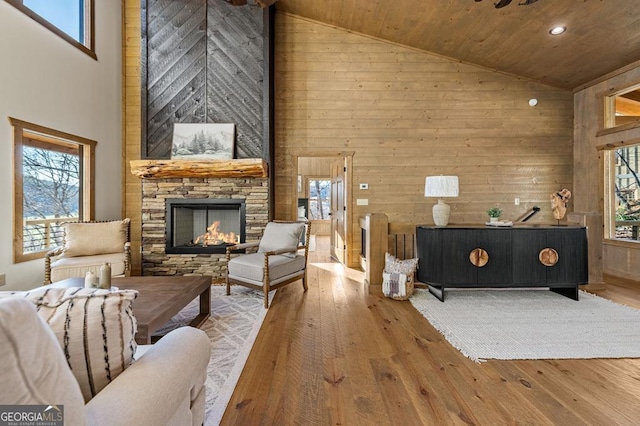 living area featuring wooden walls, a fireplace, hardwood / wood-style floors, and high vaulted ceiling