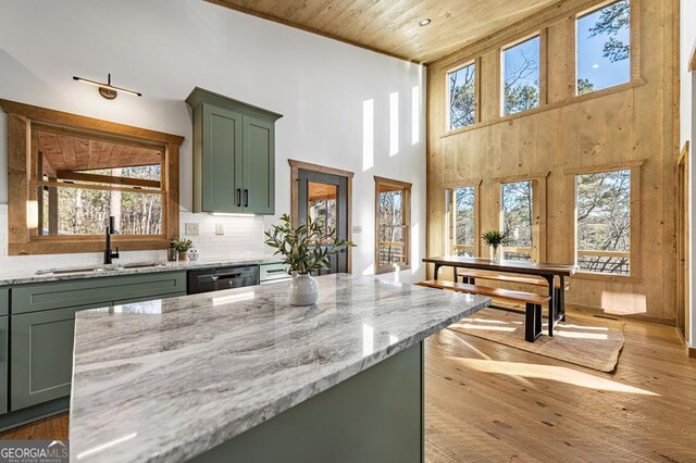 kitchen featuring a sink, light stone countertops, a wealth of natural light, and green cabinetry
