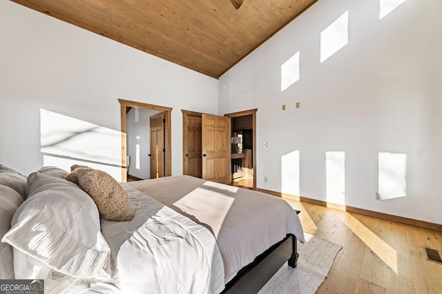 bedroom featuring baseboards, light wood-type flooring, wooden ceiling, and high vaulted ceiling