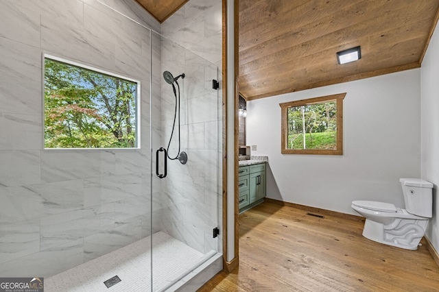 full bath featuring toilet, vanity, a marble finish shower, wood-type flooring, and baseboards