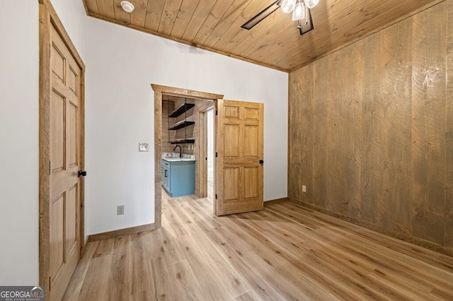 unfurnished room featuring wooden ceiling, ceiling fan, wood walls, crown molding, and light wood-type flooring