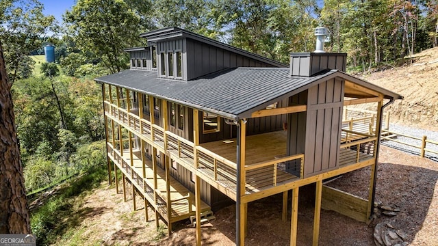 rear view of property with board and batten siding, a standing seam roof, metal roof, and a wooden deck