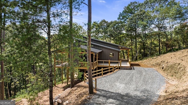 rear view of house featuring a deck and gravel driveway