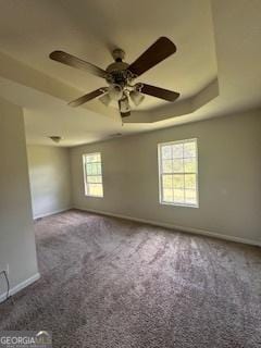 carpeted spare room with a ceiling fan, baseboards, and a raised ceiling