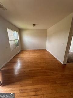 spare room featuring baseboards and wood finished floors