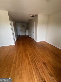 interior space featuring baseboards, an inviting chandelier, and wood finished floors