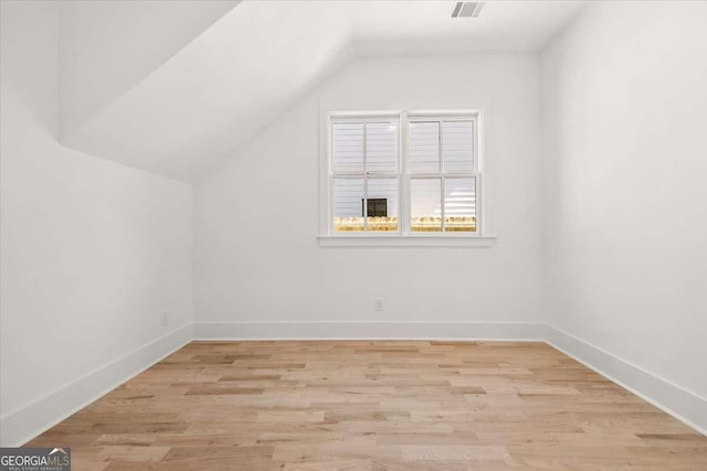 additional living space featuring lofted ceiling, baseboards, and light wood finished floors