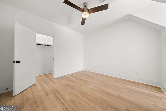 unfurnished bedroom with a closet, light wood-type flooring, baseboards, and lofted ceiling
