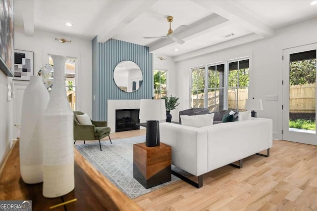 living room featuring beam ceiling, visible vents, wood finished floors, and ceiling fan