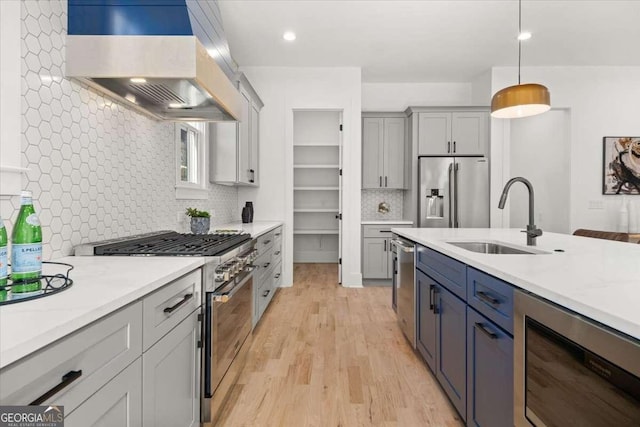 kitchen with light wood-style flooring, a sink, high quality appliances, backsplash, and premium range hood