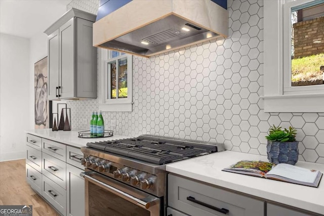 kitchen with light countertops, high end stainless steel range, premium range hood, and gray cabinets