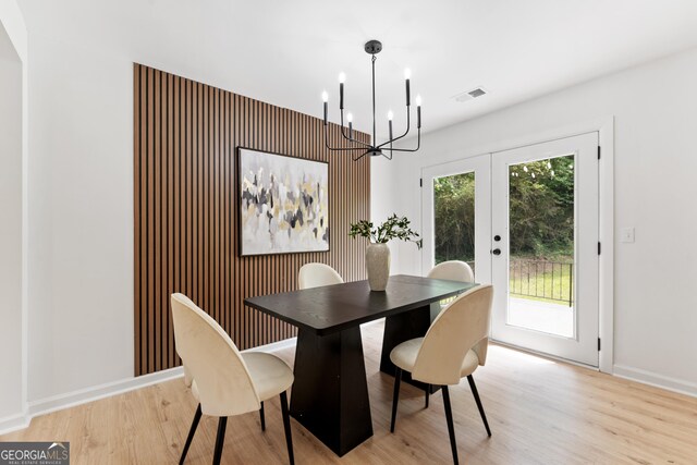 dining space with french doors, light wood-style flooring, visible vents, baseboards, and a chandelier