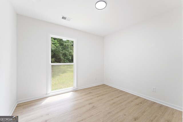spare room featuring light wood-style floors, visible vents, and baseboards