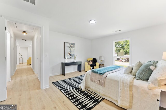 bedroom featuring baseboards, light wood finished floors, visible vents, and attic access