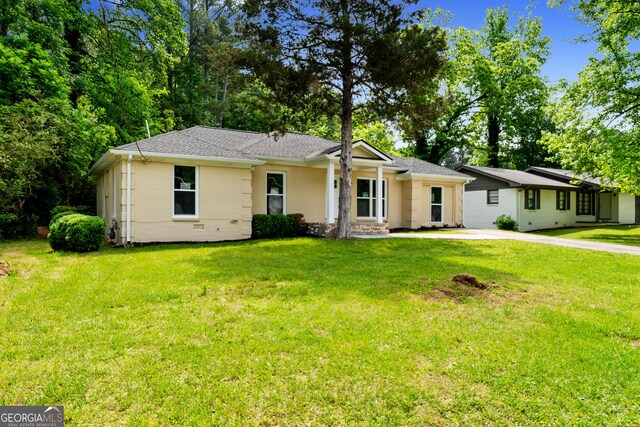 ranch-style home with a front lawn and roof with shingles
