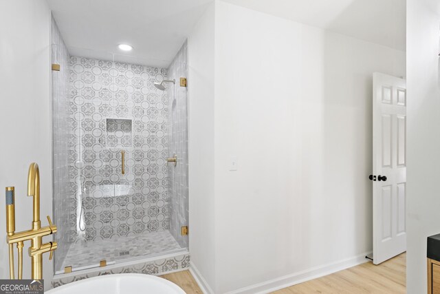 full bath with recessed lighting, baseboards, tiled shower, and wood finished floors