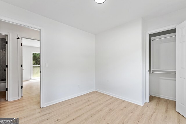 unfurnished bedroom with light wood finished floors, baseboards, and a closet