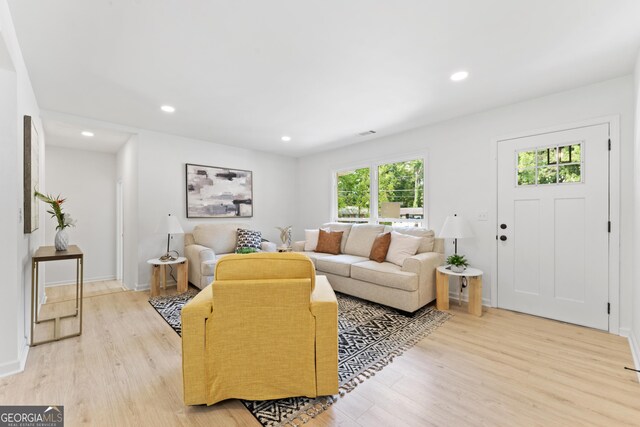 living room with light wood-style floors, visible vents, baseboards, and recessed lighting