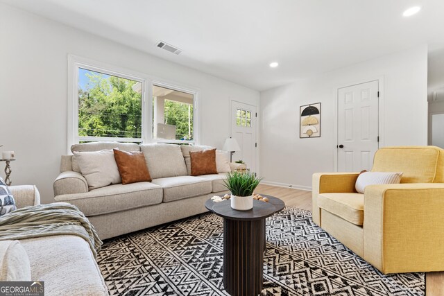 living room featuring a healthy amount of sunlight, visible vents, and light wood-style floors