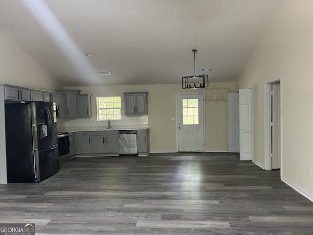 kitchen with lofted ceiling, gray cabinetry, stainless steel dishwasher, dark wood-style flooring, and black fridge