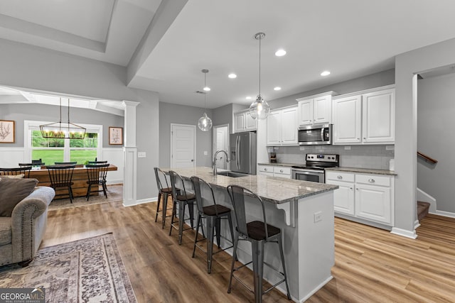 88 Carl Williams Rd, Senoia, GA 30276 - kitchen featuring stainless steel appliances, a breakfast bar, light wood-style floors, light stone counters, and recessed lighting