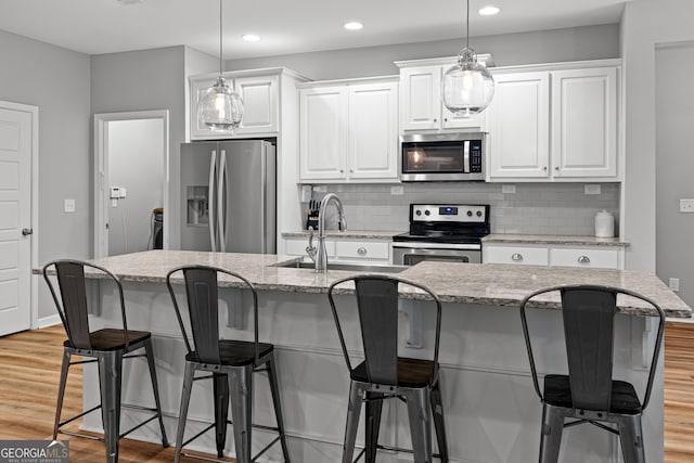 88 Carl Williams Rd, Senoia, GA 30276 - kitchen with stainless steel appliances, white cabinetry, a sink, backsplash, and a kitchen island with sink