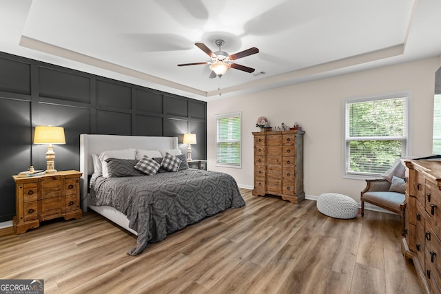 88 Carl Williams Rd, Senoia, GA 30276 - bedroom with a tray ceiling, light wood-style flooring, multiple windows, ceiling fan, and a decorative wall