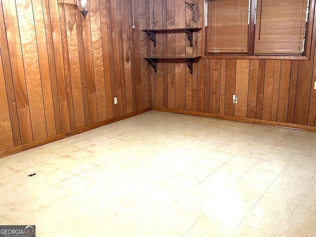 empty room featuring wood walls, baseboards, and tile patterned floors