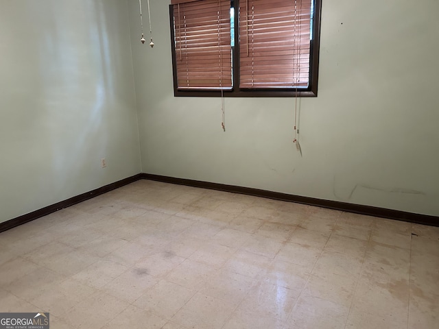 spare room featuring tile patterned floors and baseboards