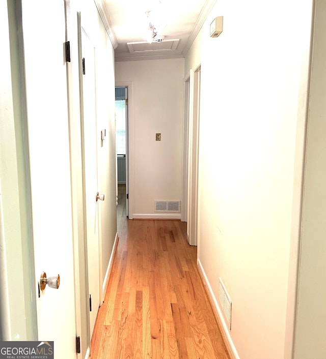 hallway featuring crown molding, light wood-style flooring, visible vents, and attic access