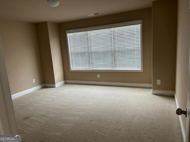 empty room with light carpet, baseboards, visible vents, and a healthy amount of sunlight