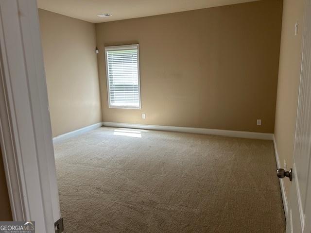 spare room featuring carpet flooring and baseboards