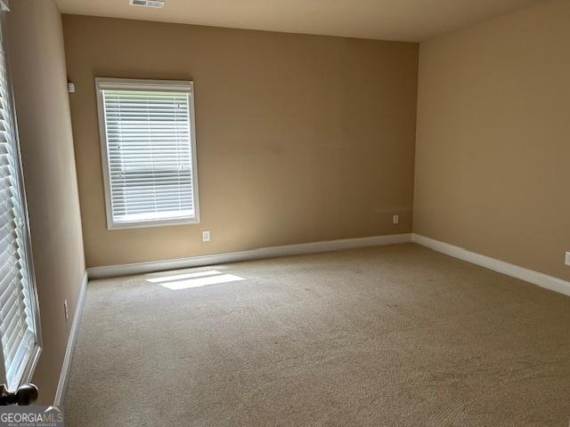 unfurnished room featuring baseboards, visible vents, and carpet floors