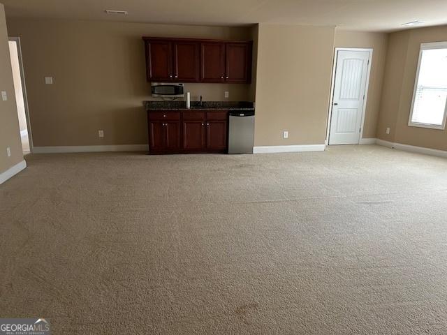 interior space featuring dark countertops, appliances with stainless steel finishes, light carpet, and baseboards