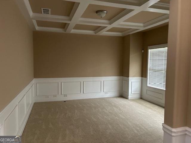 carpeted empty room with coffered ceiling, beam ceiling, a wainscoted wall, visible vents, and a decorative wall