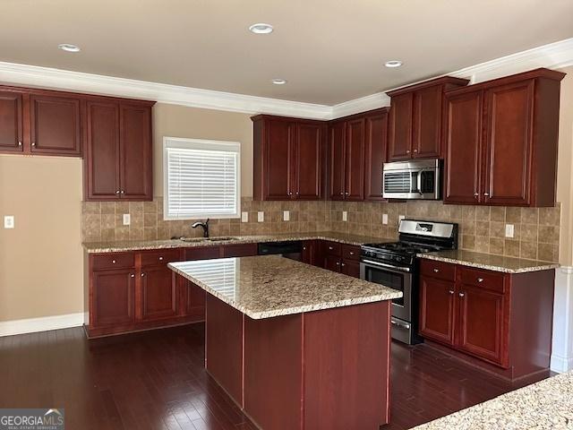 kitchen with stainless steel appliances, light stone countertops, dark wood-style floors, and a sink