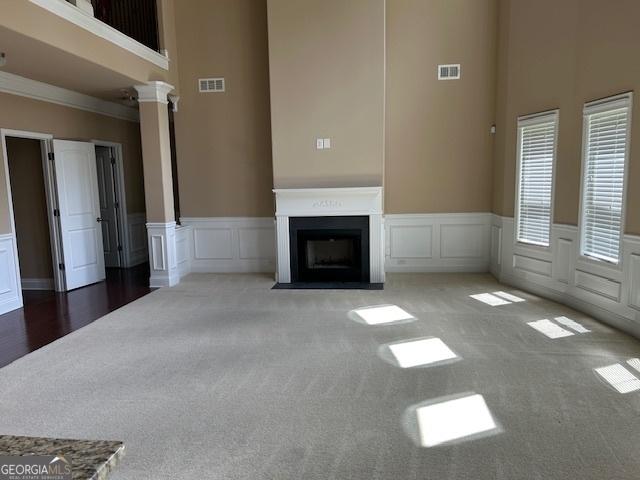unfurnished living room featuring visible vents, carpet floors, and a towering ceiling