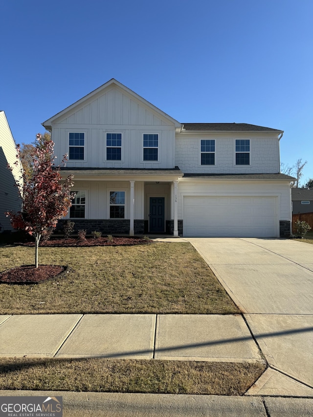 traditional-style home featuring concrete driveway, board and batten siding, a front lawn, and an attached garage