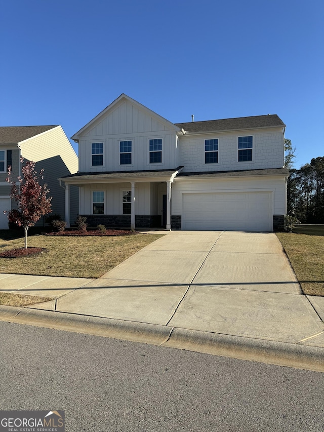 traditional-style house with board and batten siding, an attached garage, stone siding, and driveway