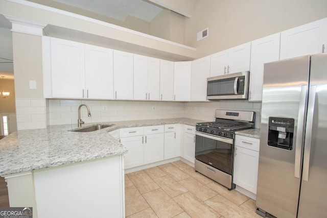 kitchen featuring a sink, a peninsula, visible vents, backsplash, and appliances with stainless steel finishes