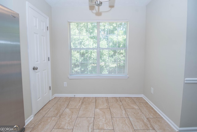 unfurnished room with a chandelier and baseboards